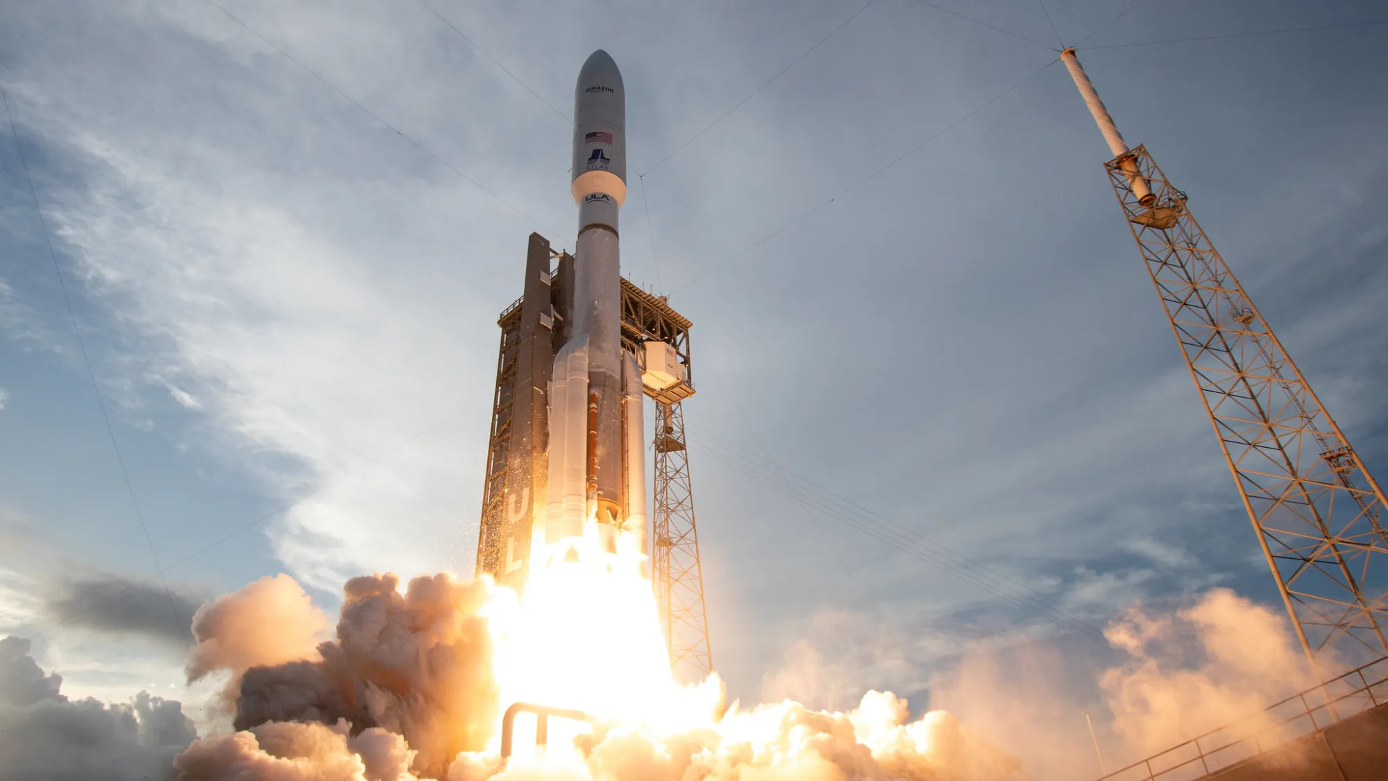 eine große weiße Rakete startet in einen wolkenverhangenen blauen Himmel